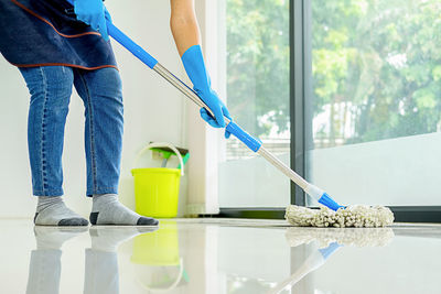 Low section of woman moping floor at home