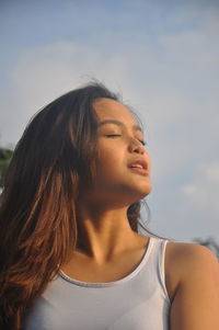 Close-up portrait of young woman against sky