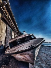 Abandoned boat moored on beach against sky