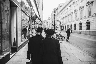 Rear view of people walking on street in city