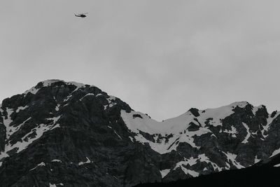 Low angle view of bird flying in mountain against sky