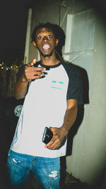 Portrait of a smiling man standing against wall at night