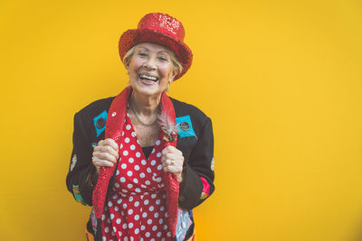 Portrait of smiling young woman against yellow wall