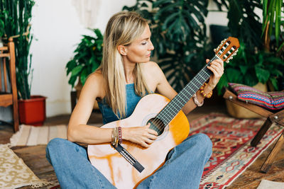 Young female guitarist playing the guitar sitting on the floor
