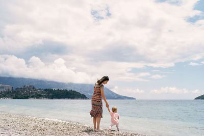 Rear view of women on beach against sky