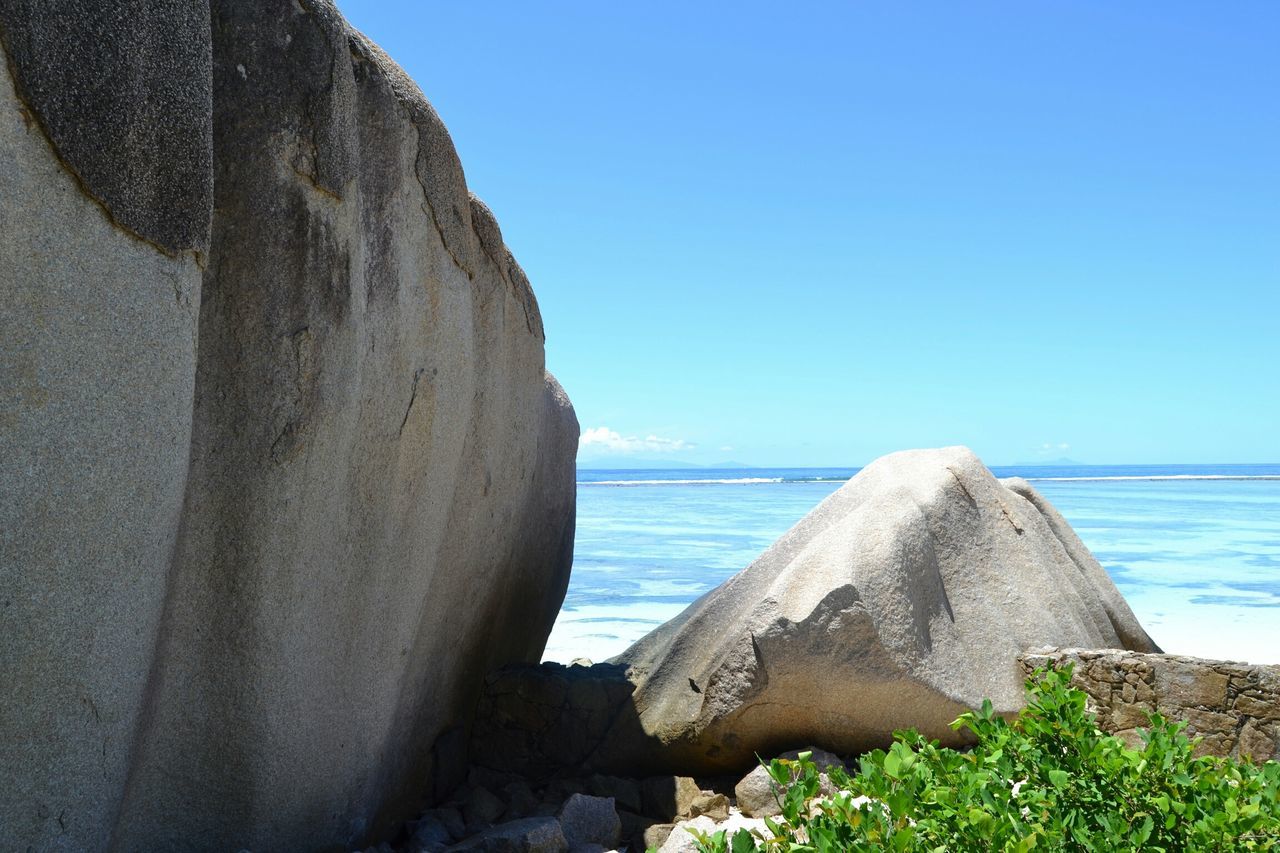 sea, clear sky, water, horizon over water, blue, copy space, scenics, tranquil scene, nature, beauty in nature, tranquility, beach, rock - object, rock formation, day, sunlight, shore, idyllic, outdoors, sky