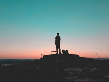 Silhouette man standing on mountain against sky during sunset