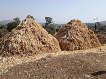 Hay bales on field against clear sky
