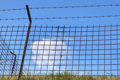 Low angle view of chainlink fence against clear blue sky