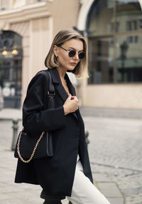 Young woman standing against wall in city