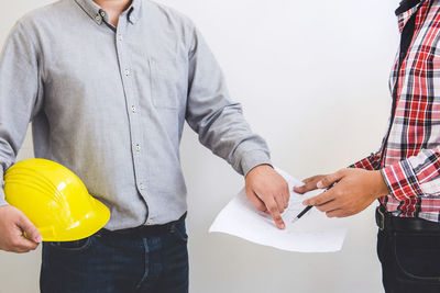 Midsection of engineers discussing over blueprint in office