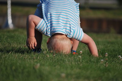 Playful baby boy with headstand on grassy field