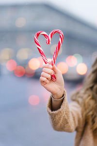 A candy cane girl in the shape of a heart against the background of blurred christmas city lights