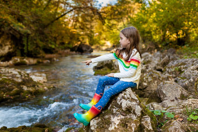 Girl sitting on rock by stream