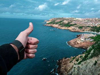 Midsection of man on rock by sea against sky