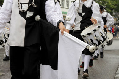 People holding flags and playing drums on street during parade in city