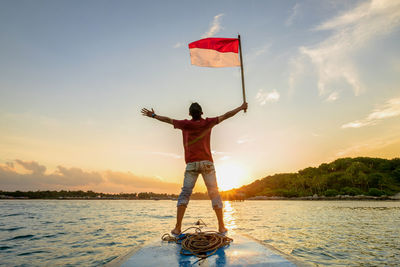 Rear view of woman with arms outstretched against sky