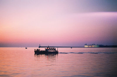 Silhouette boat in sea against sky during sunset