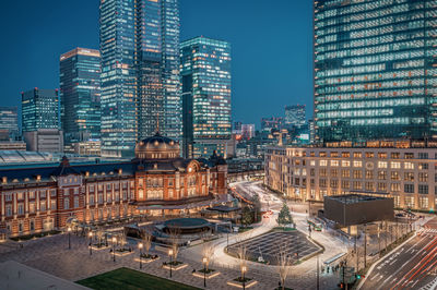 Illuminated buildings in city against sky at dusk