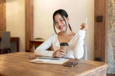 Young woman using mobile phone at table