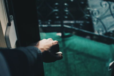 Cropped hand holding glass door handle