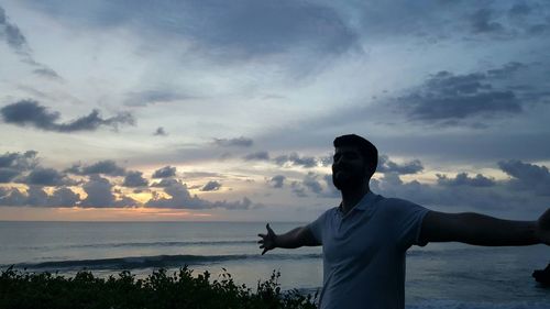 Silhouette man standing on beach against sky during sunset