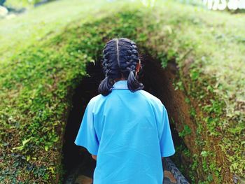 Rear view of girl standing against grassy tunnel