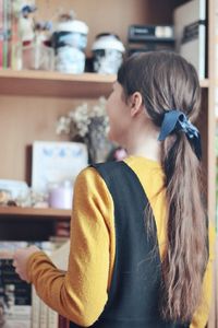 Rear view of woman with long brown hair standing at home