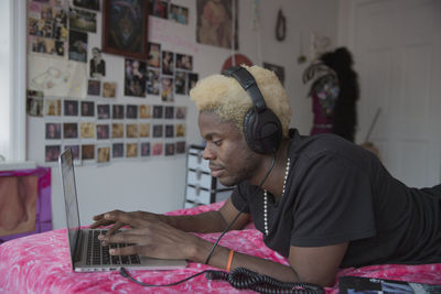 A young man wearing headphones with a laptop