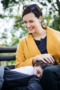 Smiling woman sitting with son at public park