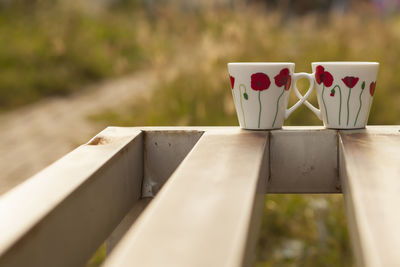Close-up of coffee cups on railing