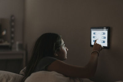 Girl adjusting temperature of bedroom through digital tablet at home