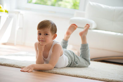 Portrait of smiling boy exercising sitting on floor at home