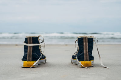 Close-up of canvas shoes on shore at beach