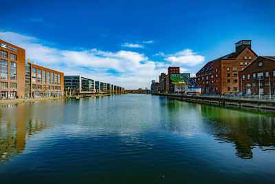 Buildings by river against sky