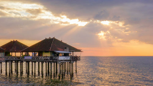 House by sea against sky during sunset