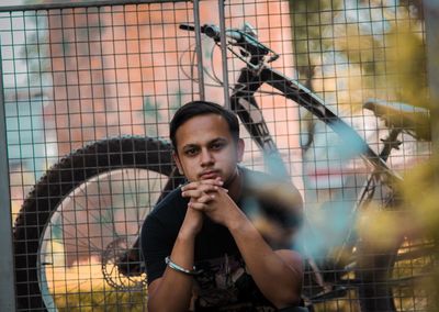 Portrait of young man looking through fence