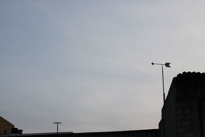 Low angle view of bird perching on building against sky