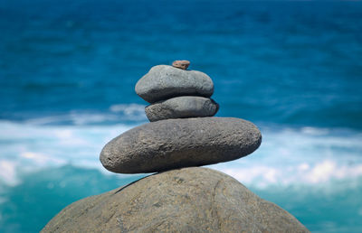 Close-up of stone stack on rock against sea