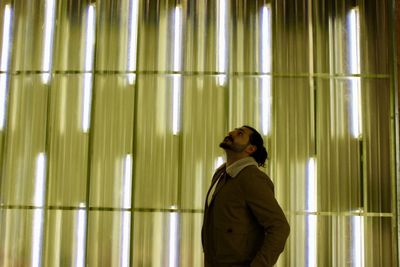 Side view of woman standing against illuminated building