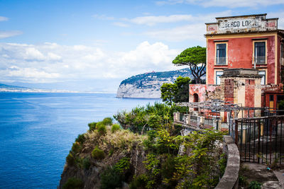 Building on mountain by sea against sky