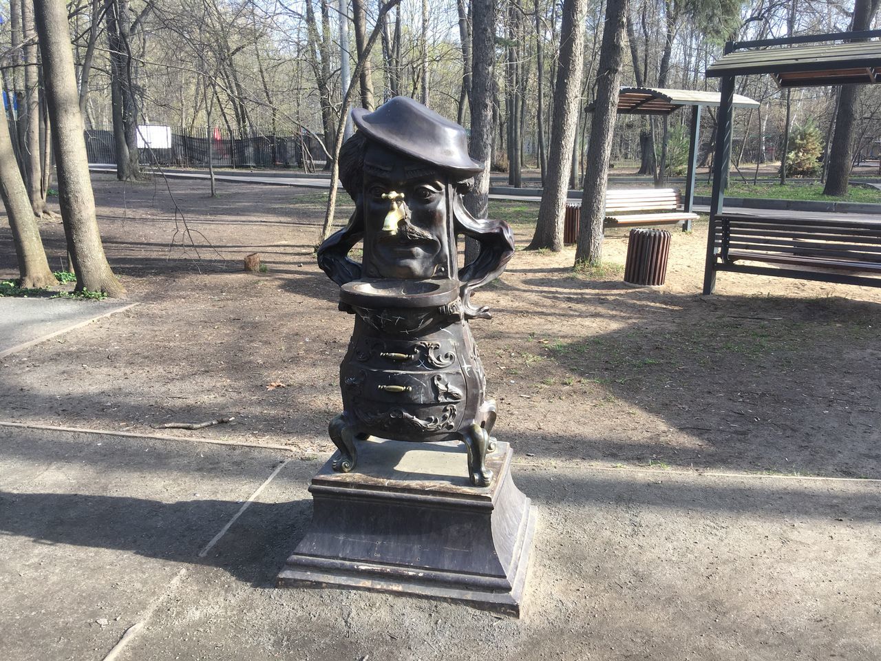 STATUE ON PARK BENCH BY TREE IN SUNLIGHT