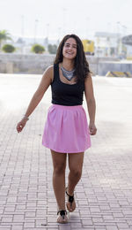 Portrait of a smiling young woman standing on footpath