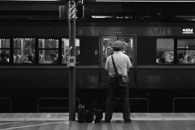 Rear view of man standing at railroad station