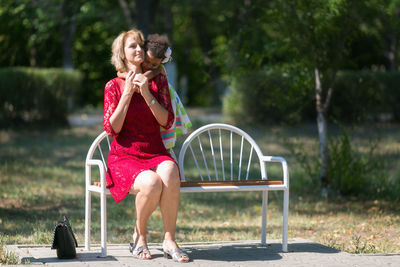 Mother with cute daughter on bench in park