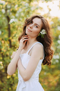 A cute happy young woman with a hairstyle in a white dress is walking enjoying nature in the summer