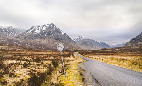 Road by mountains against sky