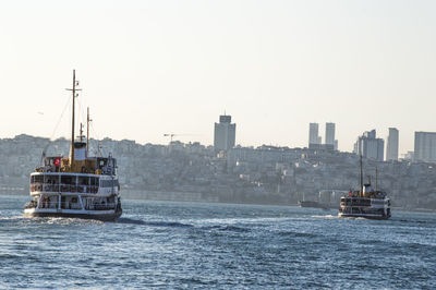 Ferry boats sailing in river against clear sky