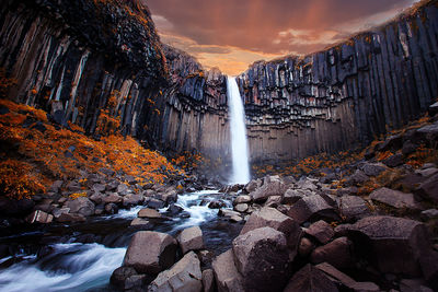 Scenic view of waterfall against sky during sunset