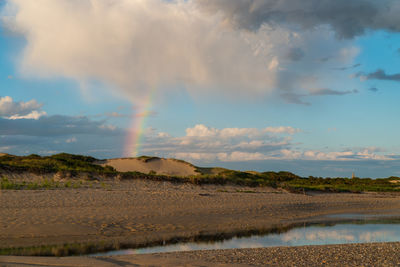 Scenic view of rainbow over lake against sky